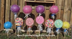 candy lollipops are on sticks in front of a wooden fence with paper lanterns