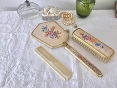 a table topped with lots of different types of hair combs and other items next to a vase filled with flowers