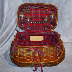 a wicker picnic basket with wine glasses and utensils in the bottom compartment