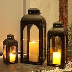 three black lanterns with lit candles in them