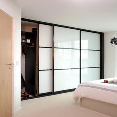 a bedroom with white walls and black trimmings on the sliding glass closet doors