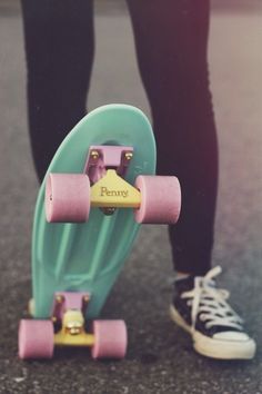 a person standing next to a skateboard with pink wheels