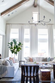 a living room filled with furniture and a chandelier hanging from the vaulted ceiling