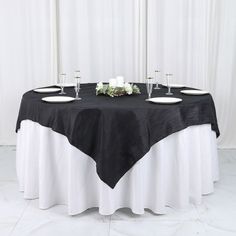 a black and white table cloth on top of a round table with two wine glasses