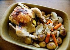 a plate with chicken, potatoes and carrots on it sitting on a wooden table