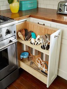 a kitchen with an oven, stove and various utensils in the cabinet drawer