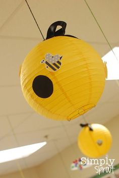 some paper lanterns hanging from the ceiling in a school hallway, with bees on them