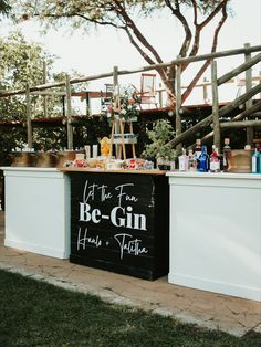 an outdoor bar with drinks on the counter and signs above it that read, let the fun be - gin have a picnic