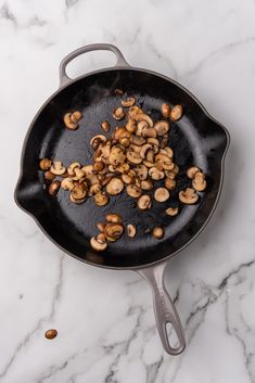 mushrooms being cooked in a skillet on a marble counter