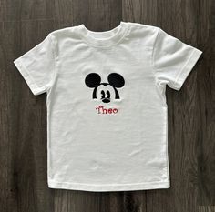 Classic Personalized Toddler T-Shirt This classic white t-shirt features an embroidered Peeking Mickey with a child's name personalized underneath. Perfect for the little one in your life! Rib trim around the neckline Machine washable Mickey Shirt, Vinyl Shirts, White Short, Atlanta Ga, Kids Tops, White T Shirt, Kid Names, Classic White, Toddler Boys