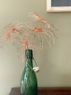 a green vase filled with flowers on top of a wooden table