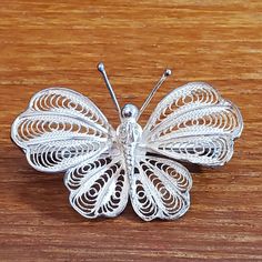 a white butterfly brooch sitting on top of a wooden table