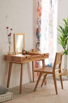 a wooden desk with a mirror on top of it next to a chair and potted plant