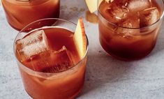 three glasses filled with ice and fruit on top of a marble countertop next to sliced apples