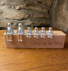 a group of little figurines sitting on top of a wooden box that says together we are family