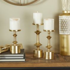 three candles are sitting on a table next to books