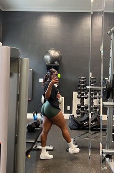 a woman taking a selfie in the gym with her cell phone and dumbbells