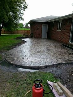 a fire extinguisher sitting in the middle of a yard next to a driveway