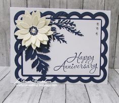 a white and blue card with a flower on the front, happy anniversary written in cursive writing