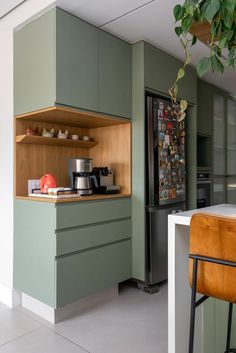 a kitchen with green cabinets and white counter tops, along with a plant in the corner