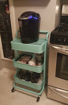 a coffee maker is sitting on top of a cart next to a stove and microwave