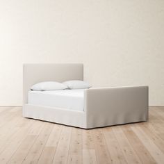 a white bed sitting on top of a hard wood floor next to a light colored wall