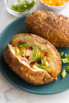 a baked potato sitting on top of a blue plate next to other food and vegetables