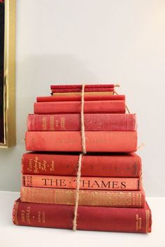 a stack of red books tied with twine on top of each other in front of a painting