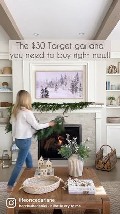 a woman walking through a living room next to a fireplace with christmas decorations on it