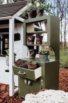 an old fashioned stove with potted plants on it's top shelf in front of a shed