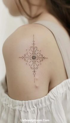 a woman's back shoulder with a cross tattoo on the upper part of her arm