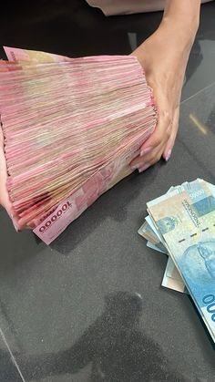 a person is holding money in their hand and stacking it on top of each other