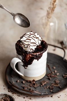 a spoon scooping some ice cream into a cup filled with chocolate and marshmallows