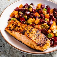 a white plate topped with meat and veggies next to a bowl of fruit