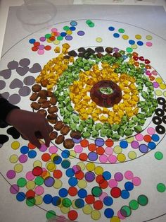 a child's hand is pointing at an art project made out of candy and candies