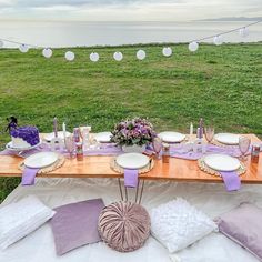 a table set up with plates and napkins for an outdoor dinner by the water