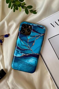 a blue phone case sitting on top of a white sheet next to a book and plant