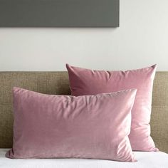 two pink pillows sitting on top of a bed next to each other in front of a painting