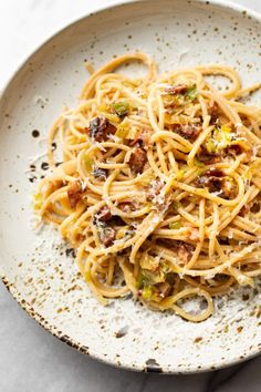 a white plate topped with pasta and bacon