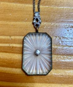 "Antique Art Deco rhodium Filigree Camphor Glass pendant. The center contains a rectangular camphor glass that is bezel set into a sawtooth edged mounting and the center has a tiny diamond shaped finding containing a small Genuine Diamond (tested). Not marked, assumed to be rhodium plated or some sort of plating, not tested. It hangs from a large fancy Filigree bail. With the bail the pendant section measures a bit over 1.5\" tall by 3/4\" wide. It hangs off a simple silver colored cable chain with a squeeze clasp that is 18\" long. In nice shape, slight surface wear in spots, some dirt and slight wear on the glass, diamond is sparkly and the filigree bail is large and wide so it can hold a much wider style chain. Ask questions and look at my pictures." Classic White Jewelry With Rectangular Pendant, White Sterling Silver Art Deco Jewelry, White Engraved Rectangular Pendant Necklaces, White Engraved Rectangular Pendant Necklace, Classic White Rectangular Necklace, Silver Octagon Engraved Jewelry, Silver Rectangular Etched Necklace, Elegant Nickel-free Rectangular Necklace, Collectible Etched Rectangular Jewelry