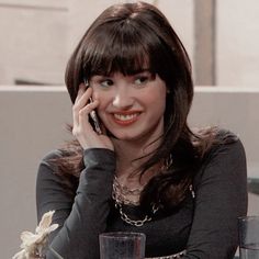 a woman sitting at a table talking on her cell phone