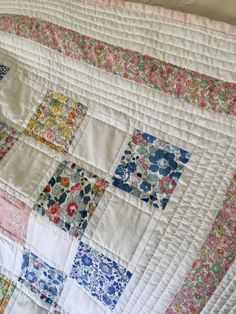 an old quilt is laying on top of a bed sheet that has been made into a baby quilt