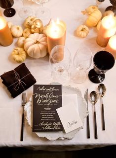 the table is set with candles, napkins and place settings for an elegant fall wedding