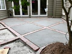 a concrete patio being built in front of a house with a tree on the side