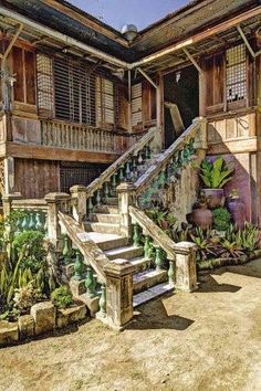 an old house with some plants in the front yard and stairs leading up to it