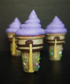 three cupcakes with purple frosting on top are sitting in ice cream cones