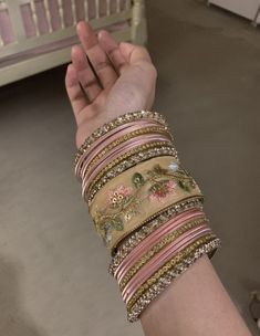 a woman's arm with bracelets on it and a crib in the background