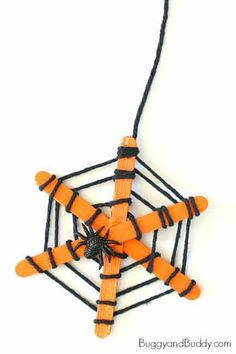 an ornament made out of orange and black string with a spider on it