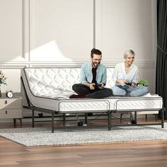 two people sitting on top of a white bed