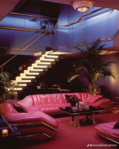 a living room filled with pink couches under a stair case next to a table